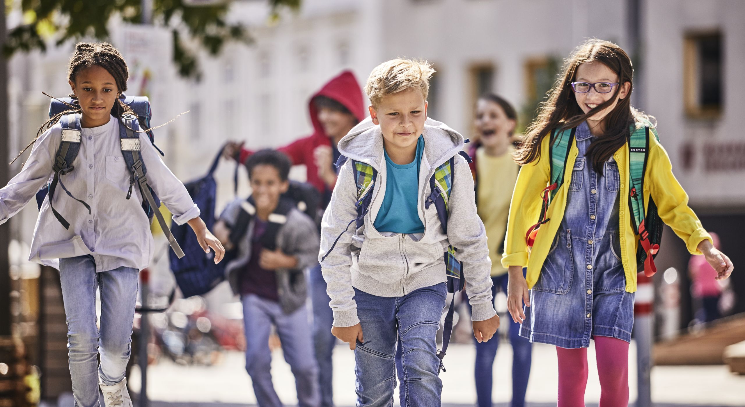 Ein Bub und zwei Mädchen auf dem Schulweg